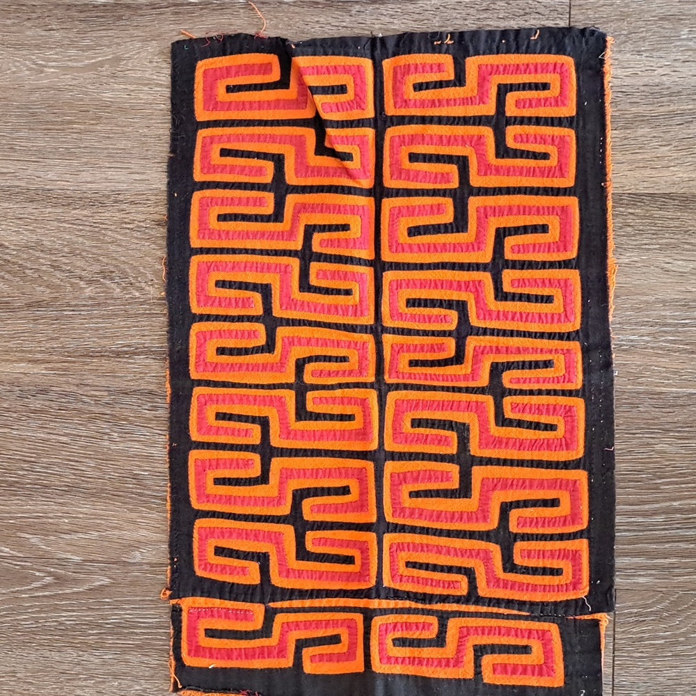 Red and Orange on Black Mola. Geometric Patterned Textile.
